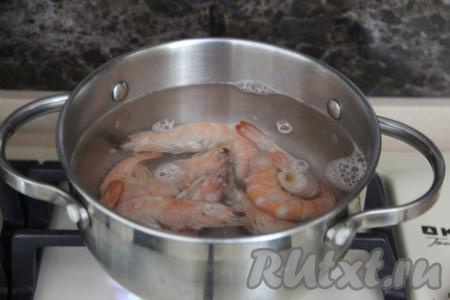 В кастрюле вскипятить воду, подсолить. В кипящую воду выложить размороженные креветки и варить их с момента закипания на небольшом огне минуты 2. Затем достать креветки из воды, дать остыть.