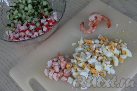 В салатнике соединить нарезанные крабовые палочки и огурцы. Яйца тоже нарезать на мелкие кубики. Некрупно нарезать креветки (при желании несколько креветок можно оставить целыми для украшения блюда, но это необязательно).&nbsp;