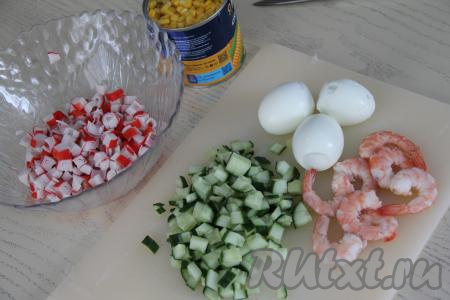 Крабовые палочки достать из упаковки. Огурец и крабовые палочки нарезать на мелкие кубики. Креветки очистить от панциря, головы и хвоста. Если креветки крупные, то вынуть тонкую кишку, проходящую поверх хвостовой части.