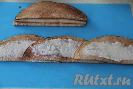 На плоскую поверхность выложить первый блин, сложенный пополам, смазать его сверху частью крема, немного отступив от краёв. На этот блин внахлёст выложить следующий блин, тоже смазать его сверху частью крема, выложить третий блинчик внахлёст, тоже смазать частью крема. Получится полоска из трёх блинов, как на фото.