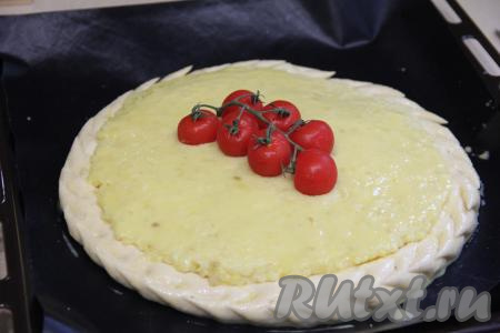 Оставить дрожжевой пирог для расстойки на 30 минут в тепле. По прошествии времени бортик теста округлится. Для красоты можно с помощью ножниц сделать надрезы по бортику. Смазать тесто и начинку пирога взбитым желтком. По желанию на серединку пирога можно выложить веточку с томатами черри.