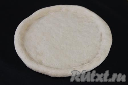 Тесто обмять и на слегка присыпанной мукой поверхности раскатать в круг диаметром примерно 28 сантиметров. Руками сформировать невысокий бортик. Я сразу раскатывала на тефлоновом коврике для выпечки (можно это сделать и на пергаменте), а затем перенесла заготовку пирога вместе с ковриком на противень.