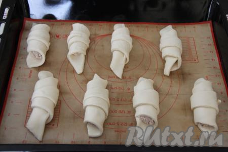 Начиная со стороны с начинкой, свернуть тесто в рулетик. Выложить сформированную слойку с курицей на противень, застеленный ковриком (или бумагой) для выпечки. Аналогично сформировать и выложить на противень на расстоянии друг от друга все слойки.