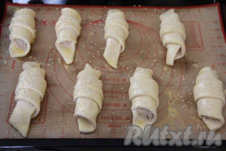 Яичный желток в небольшой ёмкости взбить до однородности вилкой. Смазать слойки взбитым желтком. По желанию, можно присыпать слойки сверху кунжутом (или маком).