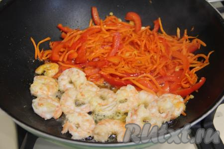 Отодвинуть обжаренные овощи на одну половину сковороды. На освободившуюся половину сковороды выложить подготовленные креветки.