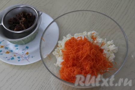 Изюм откинуть на сито, дать стечь лишней жидкости, выложить на бумажное полотенце (или на салфетки) и обсушить. В миску с творожной массой добавить натёртую морковь.