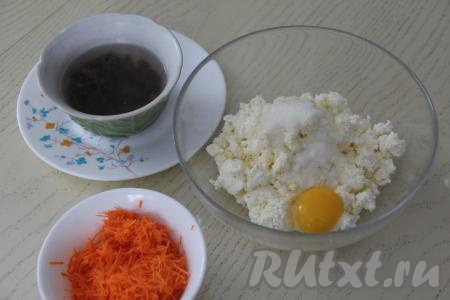 Изюм выложить в небольшую ёмкость, полностью залить его кипящей водой и оставить на 8-10 минут. Творог соединить в глубокой миске с сахаром и яйцом, перемешать творожную массу до однородности. Морковь натереть на мелкой тёрке. Если натереть морковку на обычной тёрке, она может не успеть прожариться.