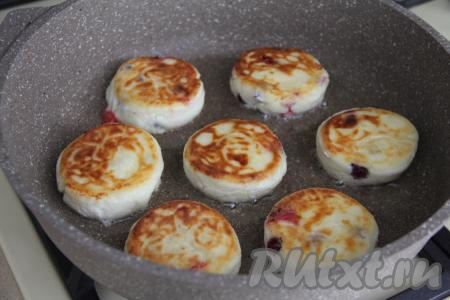 Жарить сырники с клюквой с двух сторон на среднем огне до золотистого цвета (примерно по 3-4 минуты с каждой стороны). Выключить огонь, снова перевернуть сырники, накрыть сковороду крышкой и оставить сырники пропариться на 3 минуты.