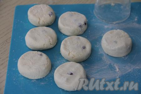 При желании заготовкам сырников, обваленным в муке, можно придать красивую форму, формируя ровные края. Я сделала заготовки ровными при помощи мерного пластикового стакана. Чтобы сделать такие ровные заготовки, нужно припылить доску мукой, выложить на муку нашу заготовку сырника, сверху накрыть сырник стаканом и быстро повращать стакан рукой по доске, делая круговые движения. В результате сырник, накрытый стаканом, приобретёт ровные края.