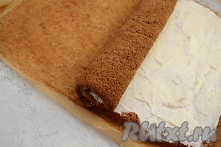 Свернуть бисквит с творожной начинкой в плотный рулет, начиная с узкой стороны коржа.