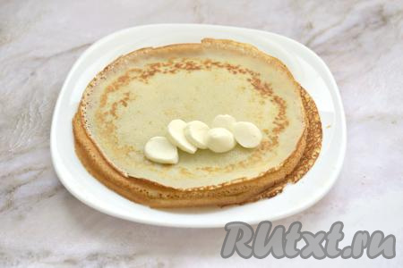 Шарики моцареллы нарезаем на кружочки. На одну сторону блина, отступив немного от краёв, выкладываем несколько кружочков моцареллы.