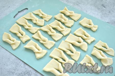 Теперь берёмся за один конец полоски и выворачиваем её через надрез. Таким образом формируем заготовки для вергунов, как на фото, из всех полосок теста.