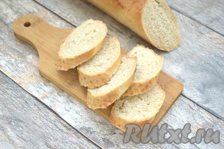 Багет нарезаем наискосок на ломтики толщиной примерно 0,7 сантиметров. Вместо багета можно взять ломтики батона.