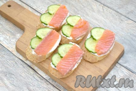 На подсушенный белый хлеб, смазанный творожным сыром, выкладываем полукружочки огурца и ломтики красной рыбы.