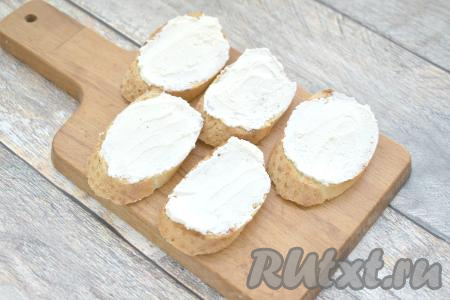 Подсушенные ломтики багета (или батона) смазываем 2 чайными ложками творожного сыра.