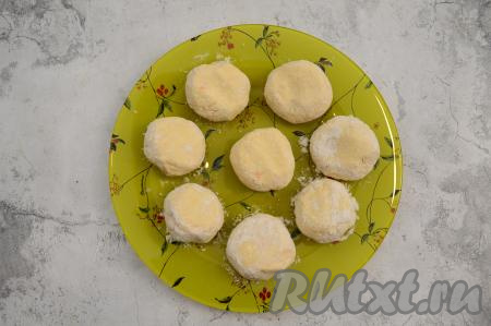 Сформированный сырник выложите на тарелку и слегка приплюсните его сверху ладонью. Таким образом руками, слегка смоченными водой, сформируйте все 8 сырников из творожной массы с курагой. Влажными руками очень удобно формировать сырники, ведь к влажным ладоням липковатое творожное тесто не пристаёт, да и сырники лучше обваливаются в муке.