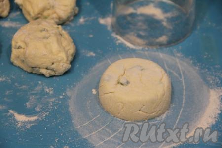 Я при помощи мерного пластикового стакана придала заготовкам сырников, обваленным в муке, идеально круглую форму. Для этого на припылённую мукой доску нужно выложить обваленную в муке заготовку сырника. Накрыть её стаканом и повращать стакан, делая круговые движения по доске. Сырник внутри стакана будет тереться о стенки и приобретёт идеально ровные края. В конце его надо будет немного приплюснуть рукой. Вот такая заготовка сырника должна получиться. С помощью того же мерного стакана придать всем сырникам форму.