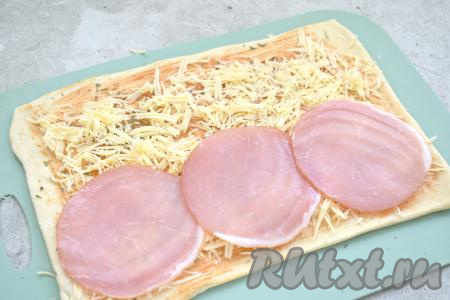 Вдоль одного широкого края теста выкладываем тонкие ломтики ветчины.
