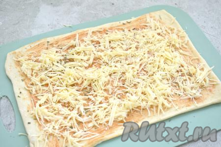 Затем тесто, смазанное кетчупом (или томатным соусом), посыпаем сыром, натёртым на крупной тёрке.