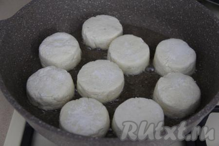 В сковороду влить растительное масло, хорошо разогреть, затем выложить сырники и жарить их на среднем огне до подрумянивания снизу (примерно 3-4 минуты).