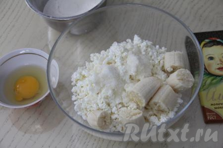 В миску выложить творог, добавить сахар и кусочки очищенного банана.