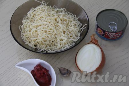 Подготовить продукты для приготовления спагетти с консервированным тунцом. Лук и чеснок почистить. Спагетти выложить в кастрюлю с кипящей подсоленной водой, перемешать, а затем после закипания воды, уменьшив огонь, варить до готовности (обычно на варку спагетти требуется 7-9 минут, но точное время варки смотрите на упаковке спагетти, которые вы готовите). Откинуть спагетти на дуршлаг, слив всю воду. Для этого блюда можно взять спагетти, оставшиеся от обеда.