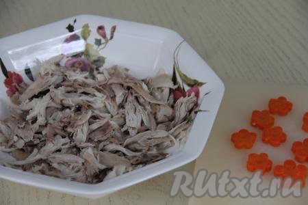 Влить желатиновую смесь в оставшиеся 400 миллилитров бульона, добавить соль и пропущенный через пресс чеснок, перемешать. Мясо отделить от кожи и костей. Затем мясо разделить на небольшие части (или нарезать). Выложить кусочки мяса в блюдо для заливного. Отваренную морковку нарезать на кружочки, можно сделать фигурные цветочки.