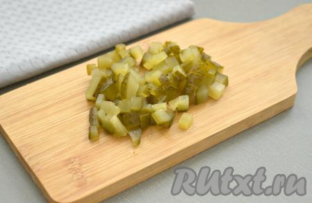 На маленькие кубики нарезаем солёный (или маринованный) огурец, тоже добавляем в миску с овощами и грибами.