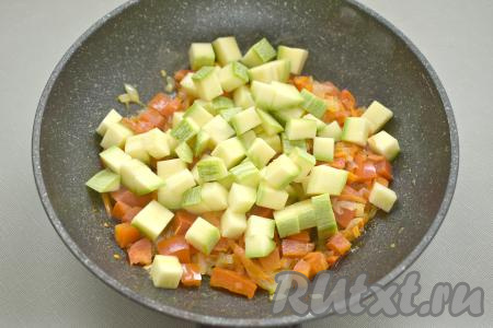Моем кабачок. Если вы будете готовить молодой кабачок, тогда очищать его от кожуры необязательно, ведь кожура у него тонкая, а семена ещё не сформировались. Если вы взяли кабачок, у которого толстая кожура и крупные семечки, тогда удалите и семена, и кожуру. 300-350 грамм подготовленного кабачка нарезаем на небольшие кубики. Добавляем кабачки в сковороду с овощами, перемешиваем, обжариваем до мягкости кабачков (на обжаривание молодых кабачков ориентировочно потребуется 7-8 минут, а вот зрелые кабачки нужно будет обжаривать 10-15 минут), время от времени помешивая.