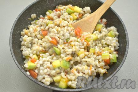 Затем перекладываем перловую кашу в сковороду с обжаренными овощами. По вкусу солим, перчим, перемешиваем, сковороду накрываем крышкой и томим блюдо 3-4 минуты на минимальном огне, периодически перемешивая, чтобы перловка равномерно прогрелась.