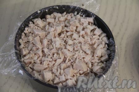 Поверх нарезанных шампиньонов выложить мелко нарезанное мясо курицы, слегка посолить.