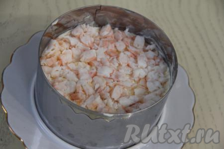 Креветки нарезать на мелкие кусочки и выложить поверх сырного слоя.&nbsp;