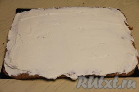 Немного крем-чиза отложить для смазывания торта сверху и по бокам, поставить в холодильник. Оставшийся крем использовать для смазывания коржей. Смазать три полоски морковного бисквита кремом.