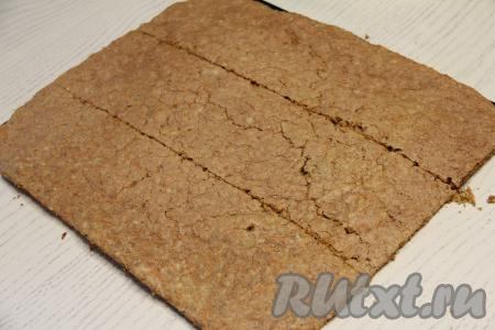 Достать противень из духовки, убрать бисквит с противня, дать немного остыть, отделить корж от пергамента (или коврика), на котором он выпекался. Оставить полностью остывать. Остывший корж разрезать на 3 равные полоски.