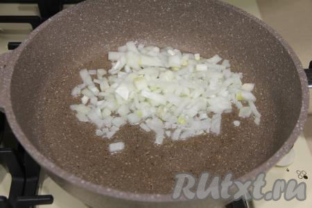 Взять достаточно объёмную и глубокую сковороду, влить в неё растительное масло, разогреть его и выложить мелко нарезанный лук. Уменьшив огонь до среднего, обжарить лук до прозрачности (в течение 3-4 минут), периодически помешивая.