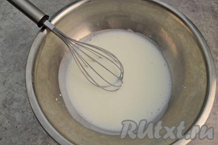 Влить кефир комнатной температуры в глубокую миску, всыпать соду, перемешать хорошо венчиком и оставить на 2-3 минуты. За это время сода начнёт вступать в реакцию с кефиром и на поверхности будут образовываться пузырьки.