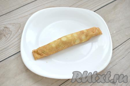 Сворачиваем блин с творожным сыром и зеленью рулетиком.