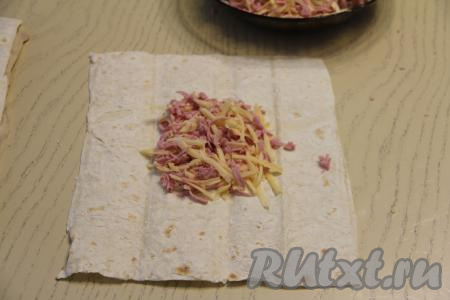 Нарезать лаваш на прямоугольники размером 21 сантиметр на 26 сантиметров. У меня получилось 7 прямоугольников из лаваша. Колбасно-сырную начинку я сразу разделила на 7 равных частей. На рабочую поверхность выложить 1 прямоугольник из лаваша. В центр прямоугольника выложить одну часть начинки.