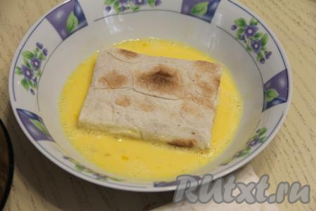В достаточно объёмной ёмкости соединить яйца с молоком, взбить вилкой до однородности. Обмакнуть конвертик из лаваша с двух сторон в яично-молочную смесь.