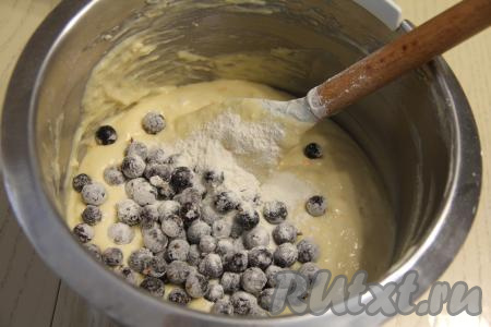 Частями добавить оставшуюся муку, каждый раз полностью вмешивая её в тесто. Добавляя муку, не забывайте учитывать густоту замешиваемого теста. Тесто должно получиться воздушным, в меру густым, напоминающим сметану средней жирности. Добавить в тесто ягоды, перемешать лопаткой. Благодаря тому, что ягоды предварительно были обвалены в муке, они будут равномерно распределяться по тесту.