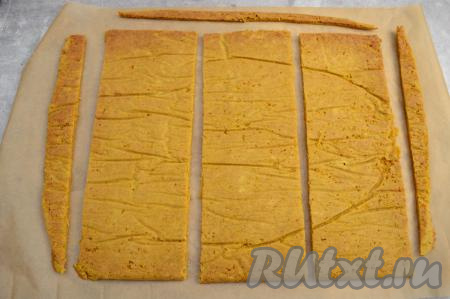 Выровнять края морковного бисквита, отрезав неровности по бокам и придавая коржу прямоугольную форму. Отрезанные неровные края понадобятся в дальнейшем для украшения торта. Разрезать корж на 3 части.