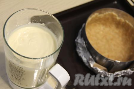 В форму для выпечки диаметром 20 сантиметров (в качестве формы я взяла кулинарное кольцо, дно которого сформировала из фольги, сложенной в несколько слоёв) выложить смесь из печенья и сливочного масла, разровнять, формируя бортики и дно основы чизкейка.