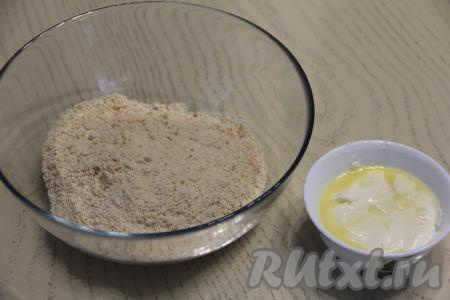 Измельчить печенье в крошку. Пересыпать крошку из печенья в глубокую миску. Если нет измельчителя, можно вложить один целлофановый пакет в другой (для прочности), внутрь пакета поместить печенье, выпустить воздух, завязать пакеты, затем прокатать поверх пакета скалкой до получения крошки из печенья.