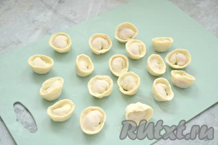 Для формирования пельменя плотно соединяем противоположные края кружка над начинкой, затем, по желанию, скрепляем концы получившегося пельмешка. Таким образом лепим остальные пельмени. Постепенно раскатываем всё тесто и, используя оставшийся фарш с зеленью, лепим все пельмени. Из указанного количества ингредиентов получается примерно 85 пельмешек.