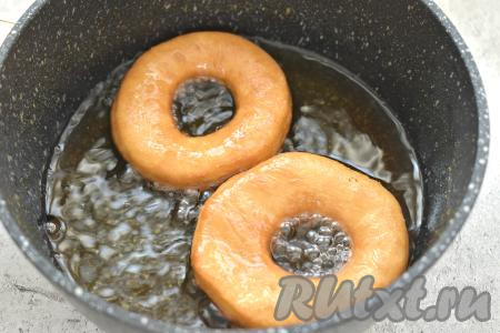 В подходящей посуде (глубокой сковороде, сотейнике, казане) сильно разогреваем достаточно большое количество растительного масла, уменьшаем огонь до среднего. Аккуратно выкладываем в горячее масло несколько заготовок пончиков. Обжариваем пончики с каждой стороны примерно по 1,5 минуты (до золотистости с каждой стороны).