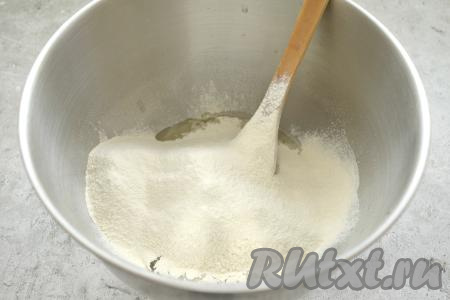 В получившуюся смесь просеиваем половину муки, перемешиваем лопаткой. Частями всыпая оставшуюся просеянную муку, перемешиваем тесто вначале лопаткой, а после того как оно начнёт собираться в ком, вымешиваем его руками в течение 7-10 минут, добавляя понемногу муку только по мере необходимости.