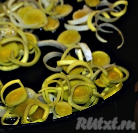 Тарелку с баклажанами отставить в сторонку, а на этой же сковороде на среднем огне в течение 5 минут обжарить очищенный и нарезанный лук (я нарезала лук порей колечками, репчатый лук можно нарезать полукольцами или четверть кольцами), не забывая помешивать время от времени.
