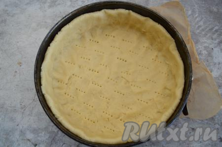 Дно разъёмной формы диаметром 22 сантиметра застелить пергаментом, бока формы смазать сливочным маслом или растительным маслом (благодаря тому, что стенки формы смазываются маслом, готовая выпечка будет лучше отходить от стенок формы). Песочное тесто распределить по дну формы, формируя высокий бортик. Тесто на дне формы наколоть вилкой (если тесто не наколоть вилкой, оно будет вздуваться во время выпечки).