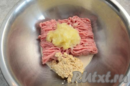 Фарш из индейки переложить в глубокую миску. Крупную луковицу очистить, натереть на средней тёрке (или пропустить через мясорубку), добавить в миску с фаршем. Сюда же выложить овсяные хлопья, отжатые от лишнего молока (или воды).