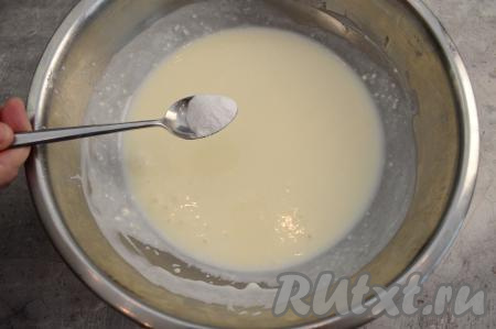 В миску с творожно-яичной массой влить кефир комнатной температуры, тщательно перемешать лопаткой. Всыпать соду, перемешать и оставить кефирно-творожную массу на 5 минут. По истечении 5 минут сода погасится, поэтому на поверхности кефирно-творожной массы появятся пузырьки.